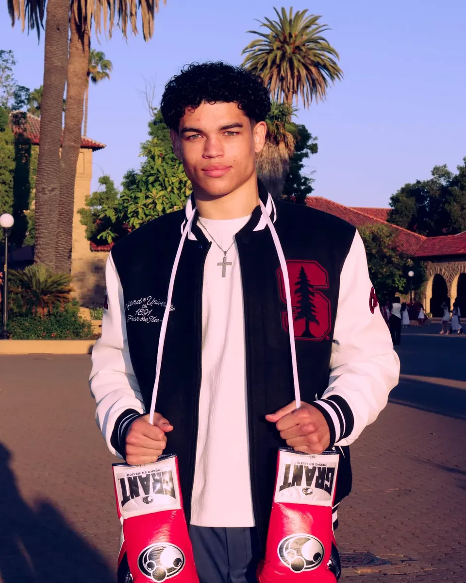 Dante Kirkman in a Stanford varsity jacket holding red boxing gloves on campus